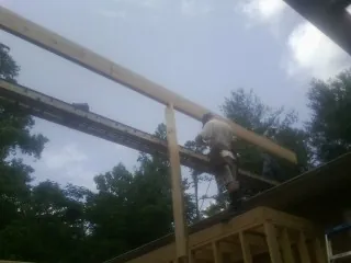 Carpenter setting a ridge beam over a new addition frame — Ice Dam Removal by Roofing Brothers in Tingley