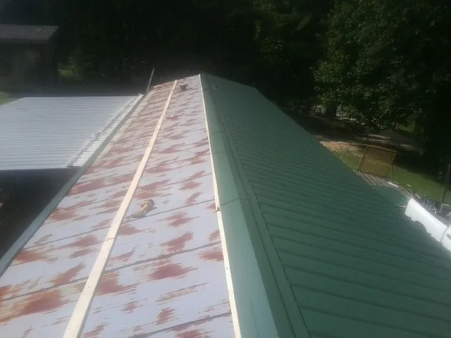 Old rusted panels beside newly installed green metal roofing — Wind Damage Roof Repair by Roofing Brothers in Tingley