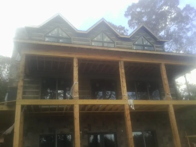 Dormers and porch framing on a large log home under construction — Roof Coating work by our crew in Tingley