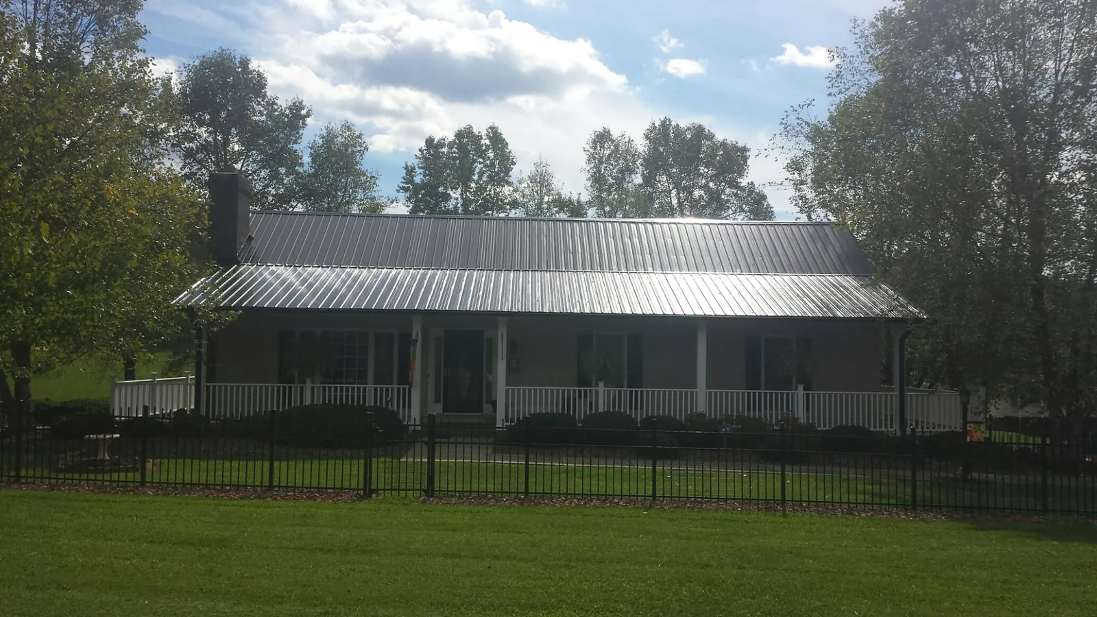 Gray metal roof on a brick ranch with a full width front porch — Gutter Guard Installation work by our crew in Tingley
