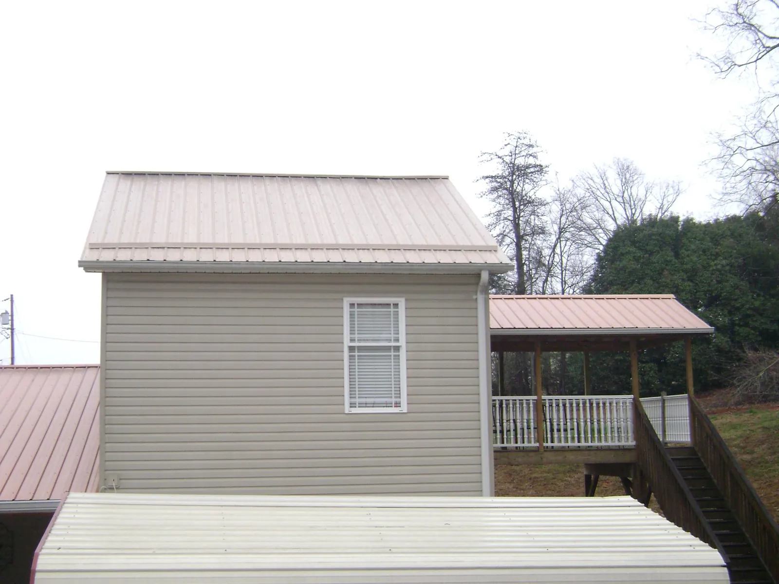 Tan metal roofs on a two story addition and attached porch, from a Roof Replacement job in Tingley
