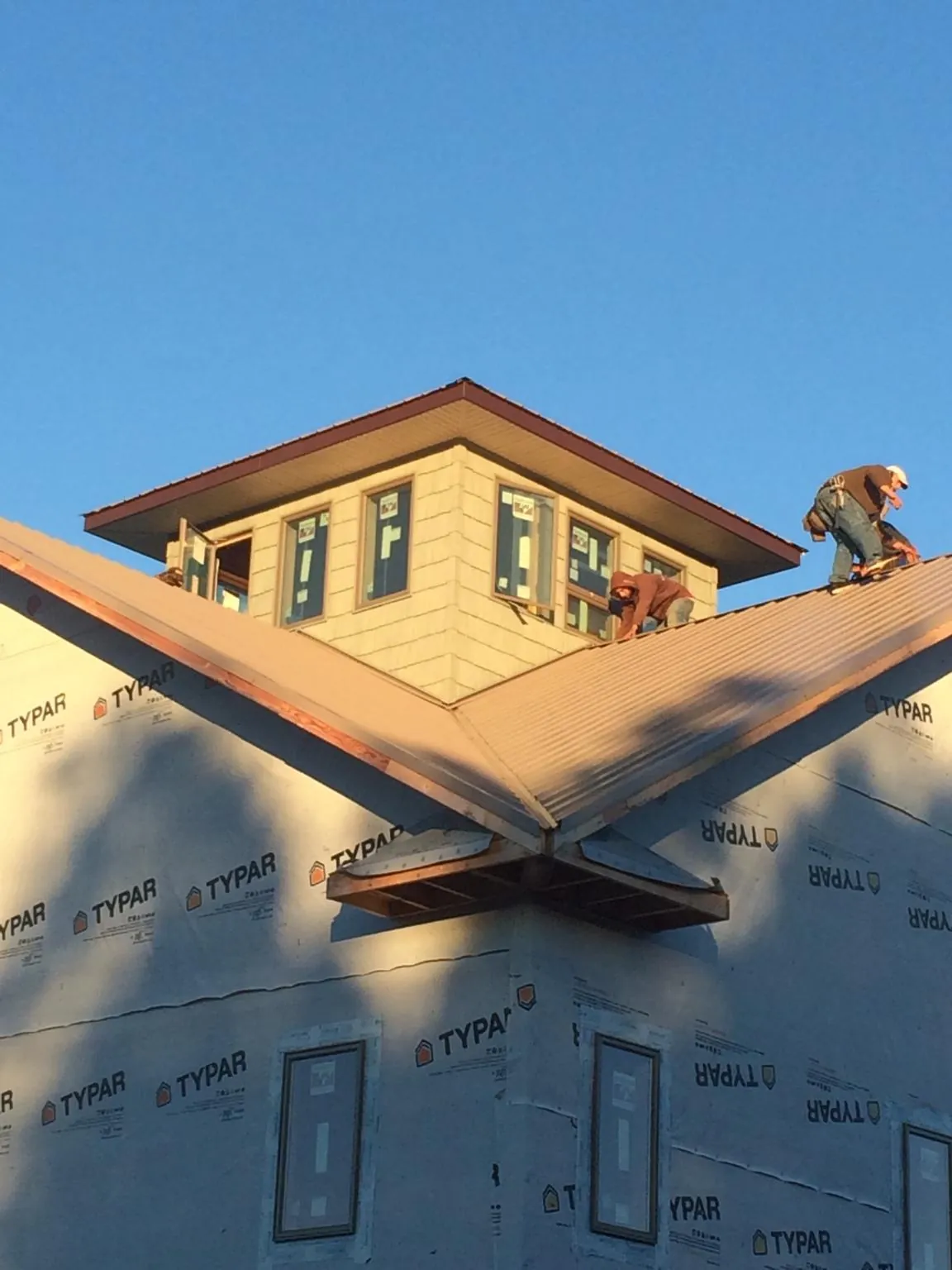 Roofers working around a rooftop cupola on a new metal roof at sunset — Roof Waterproofing in Tingley by Roofing Brothers
